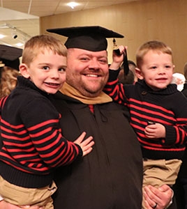 Smiling grad student celebrates commencement with his children