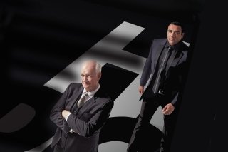 Black background with Colin Mochrie & Asad Mecci