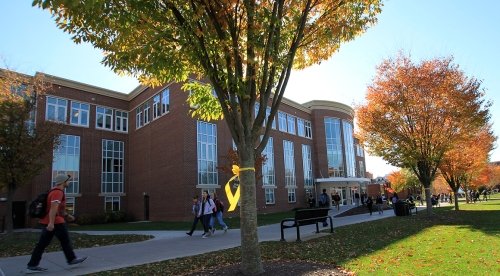 Students walk in front of Sutliff Hall during a fall afternoon 