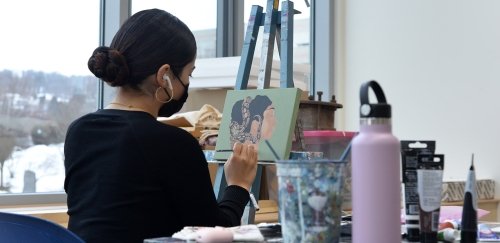 Art major works on her painting in the studio of the Arts and Administration Building