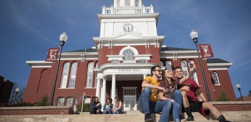Students sitting on the steps on front of Carver Hall during the Spring