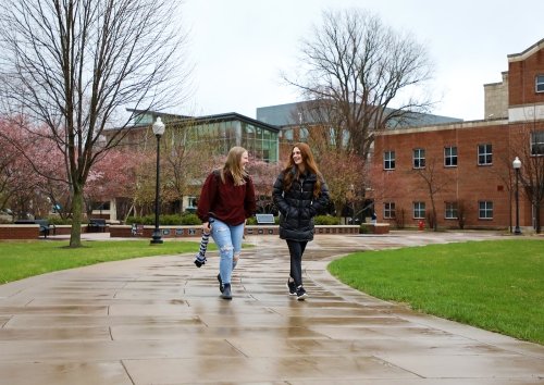Students walking in the rain across the Academic Quad in the spring