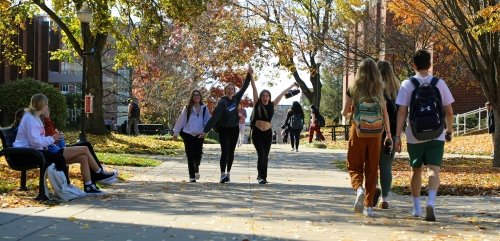 A group of friends celebrate fall on their way to class