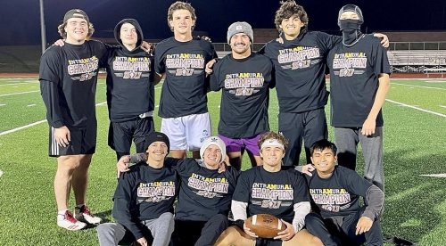 Intramural flag football poses together on the field after victory. 