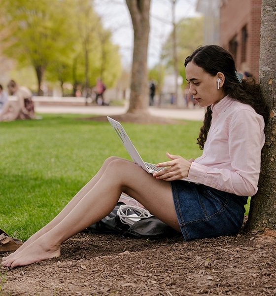 Students checks her laptop while sitting on the Quad
