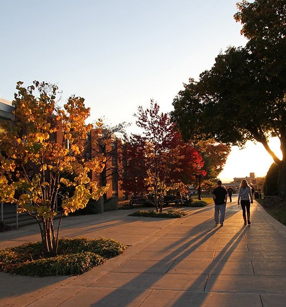 Students walk back to their residence halls as the sun sets in the fall