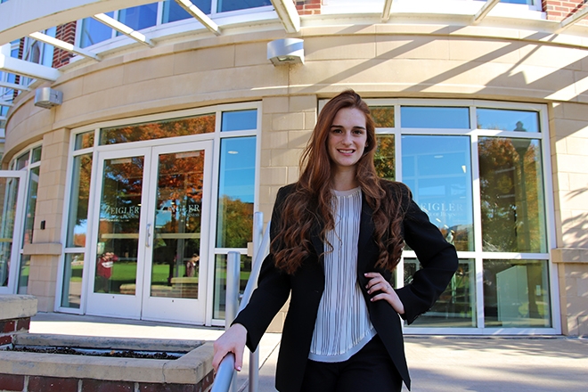 Business major displays confidence posing in front of Sutliff Hall 